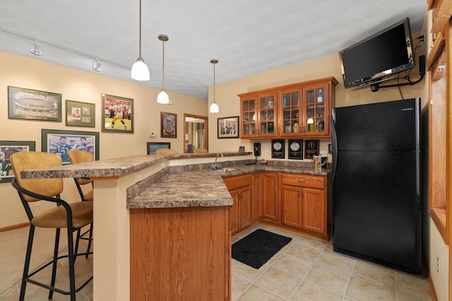 kitchen with a breakfast bar, pendant lighting, sink, kitchen peninsula, and black fridge