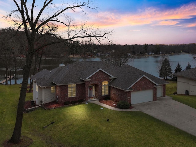 ranch-style home featuring a water view, a yard, and a garage