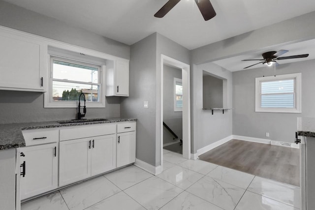 kitchen featuring dark stone counters, sink, and white cabinets