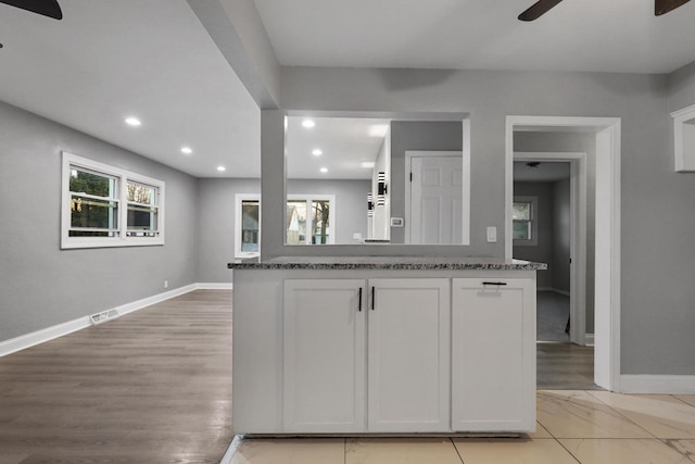 kitchen with stone counters, white cabinetry, plenty of natural light, and ceiling fan