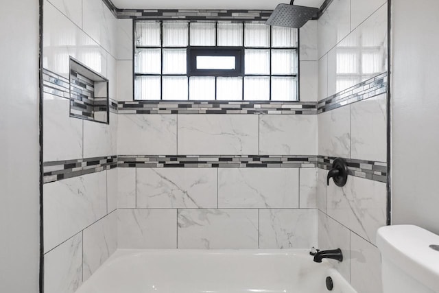 bathroom with tiled shower / bath combo and toilet