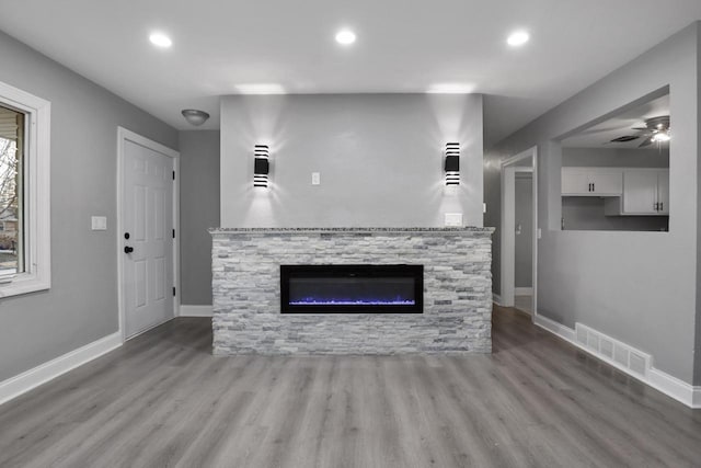 unfurnished living room featuring a fireplace, light hardwood / wood-style flooring, and ceiling fan