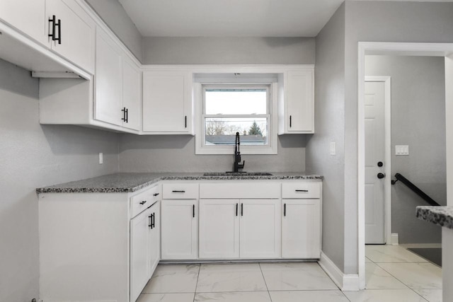 kitchen with dark stone counters, sink, and white cabinets