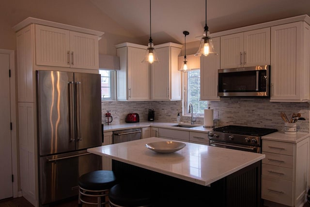 kitchen with sink, decorative light fixtures, a center island, vaulted ceiling, and high quality appliances