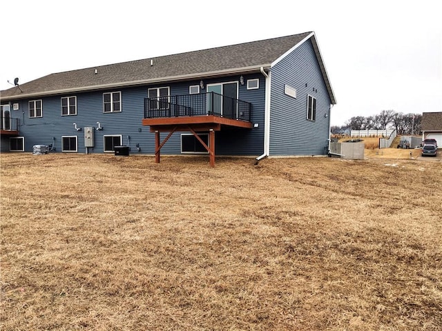 rear view of property featuring a deck, central AC unit, and a lawn