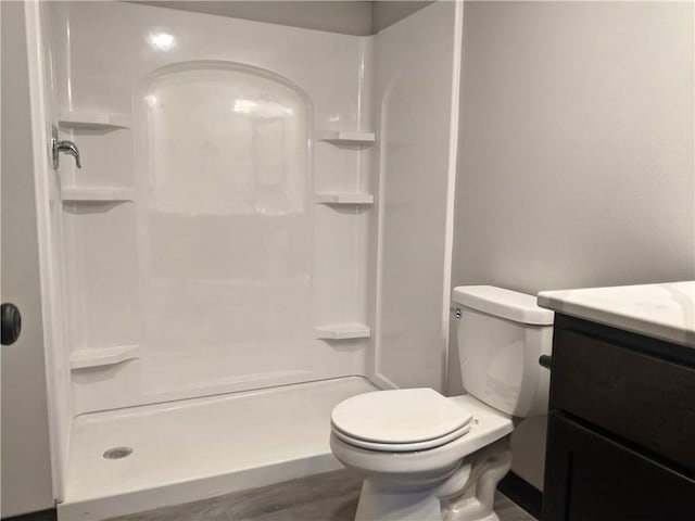 bathroom featuring a shower, hardwood / wood-style floors, vanity, and toilet