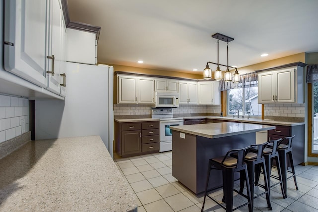 kitchen featuring light tile patterned floors, white appliances, a breakfast bar, tasteful backsplash, and a kitchen island