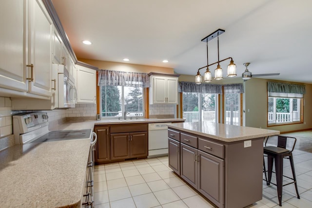 kitchen with sink, white appliances, a center island, and a kitchen bar