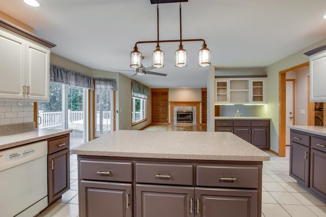 kitchen featuring white cabinetry, gray cabinetry, white dishwasher, tasteful backsplash, and a tiled fireplace