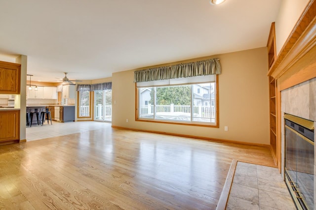 unfurnished living room featuring ceiling fan, a fireplace, and light hardwood / wood-style floors