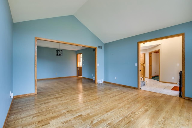 empty room featuring high vaulted ceiling and light hardwood / wood-style floors