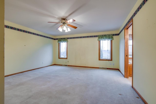 carpeted spare room featuring a healthy amount of sunlight and ceiling fan