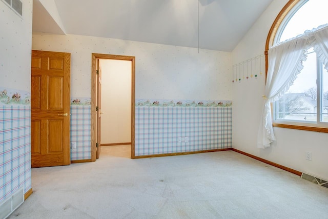 carpeted empty room featuring lofted ceiling