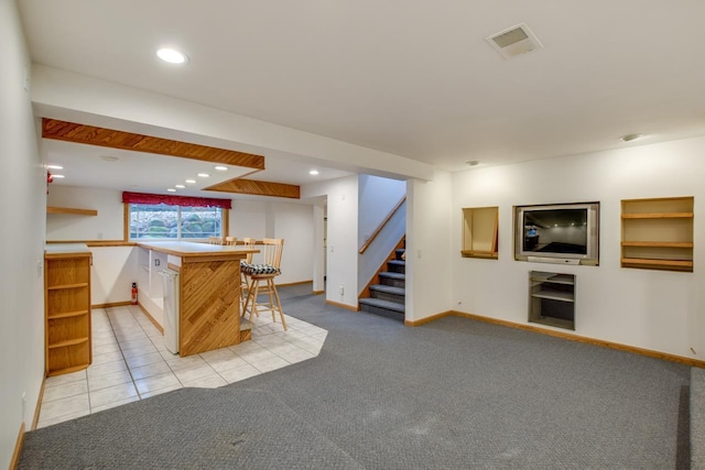 kitchen with a kitchen island, light colored carpet, a kitchen bar, and kitchen peninsula