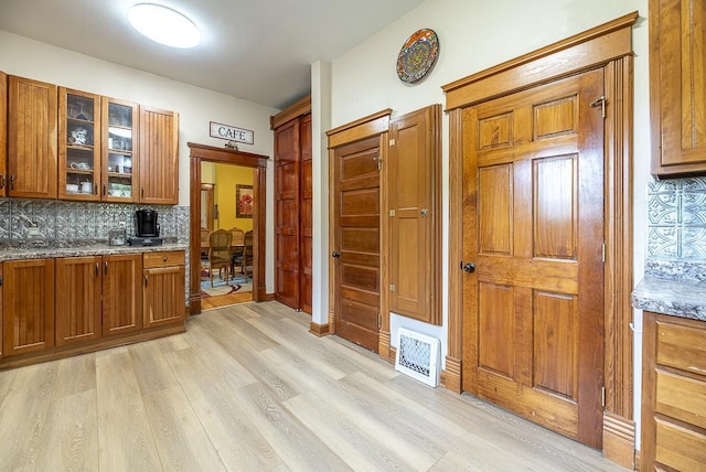 kitchen with light stone counters, tasteful backsplash, and light wood-type flooring