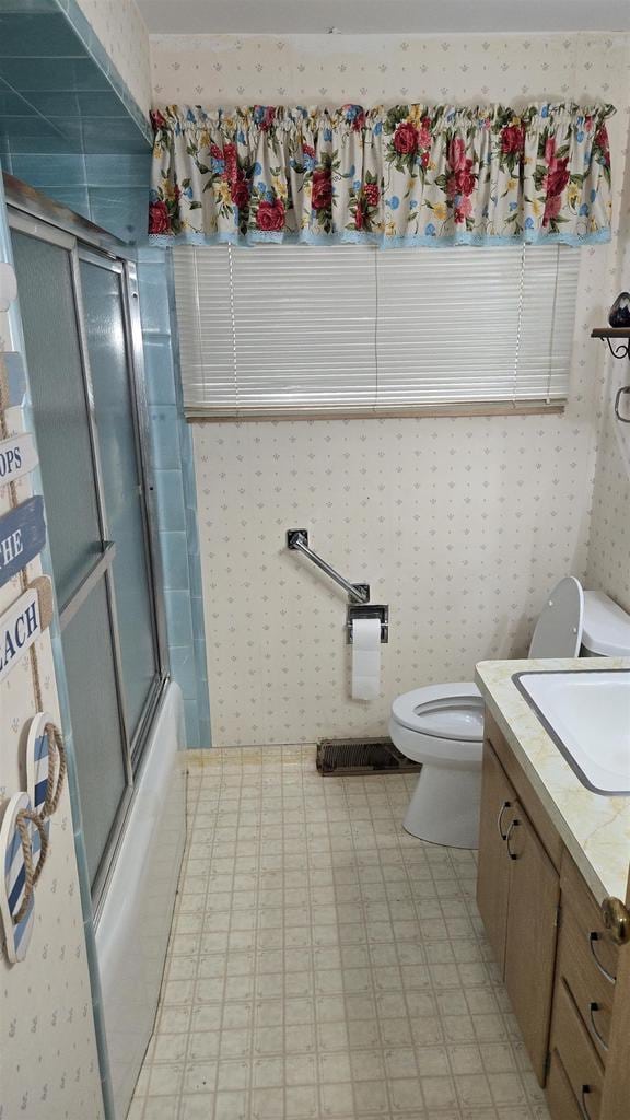 full bathroom featuring vanity, shower / bath combination with glass door, and toilet