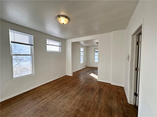 empty room with dark wood-type flooring and a textured ceiling