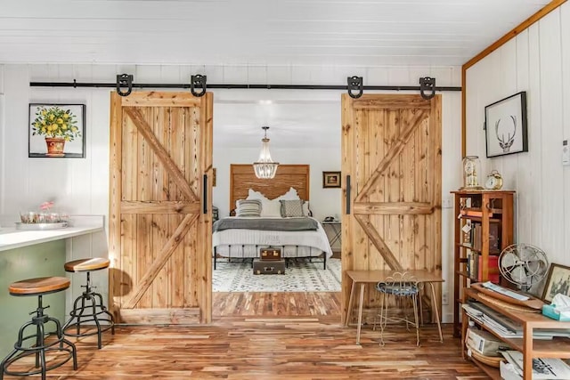 bedroom with hardwood / wood-style flooring and a barn door