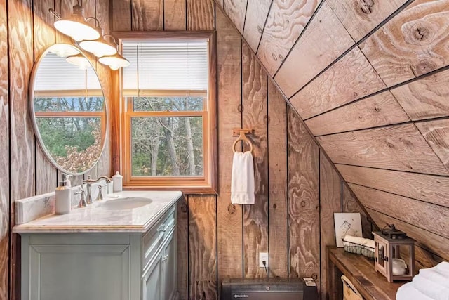 bathroom featuring vanity, vaulted ceiling, and wooden walls