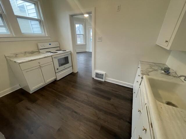 kitchen featuring sink, white range with electric cooktop, light stone counters, white cabinets, and dark hardwood / wood-style flooring