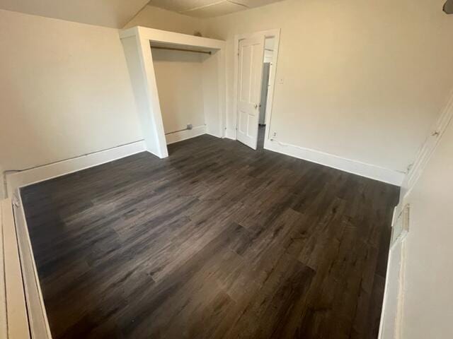 unfurnished bedroom with dark wood-type flooring and a closet