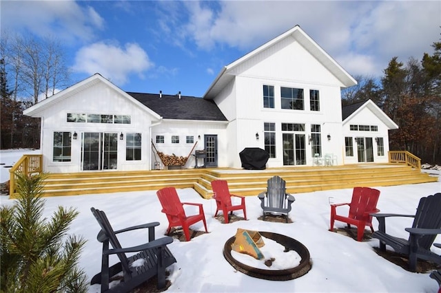 snow covered property featuring a wooden deck and a fire pit