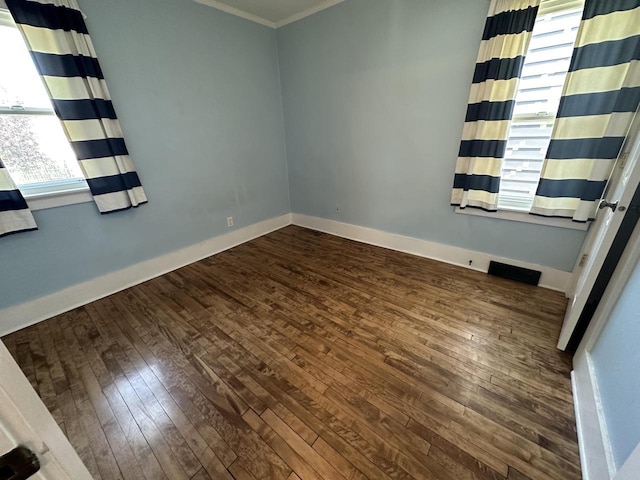 empty room with ornamental molding and dark hardwood / wood-style flooring