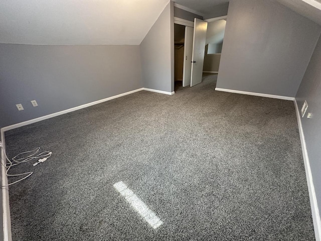 additional living space with dark colored carpet and lofted ceiling