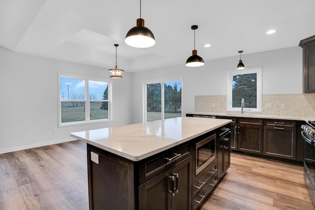 kitchen featuring a raised ceiling, sink, pendant lighting, and stainless steel appliances