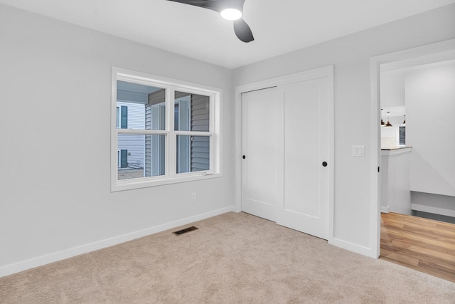 unfurnished bedroom with light colored carpet, a closet, and ceiling fan