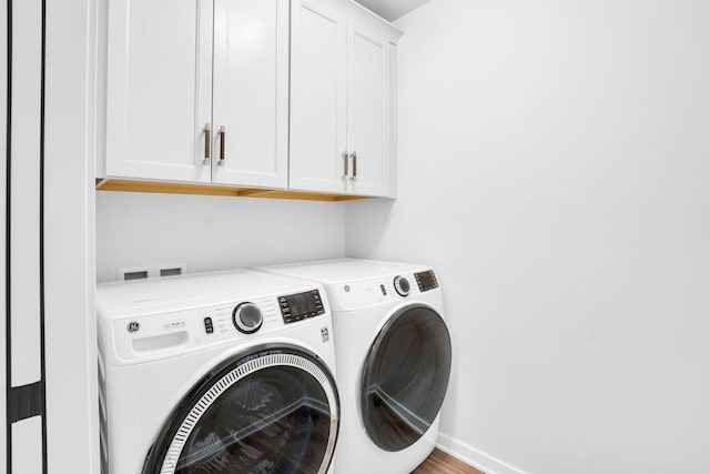 clothes washing area featuring cabinets and independent washer and dryer