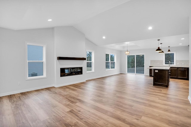 unfurnished living room with vaulted ceiling and light wood-type flooring