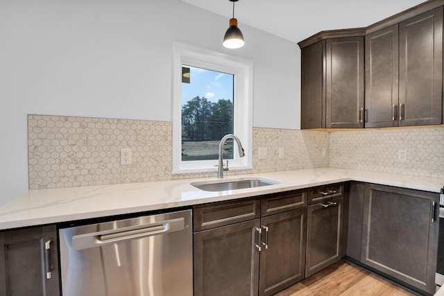 kitchen with sink, dark brown cabinets, light wood-type flooring, stainless steel dishwasher, and pendant lighting