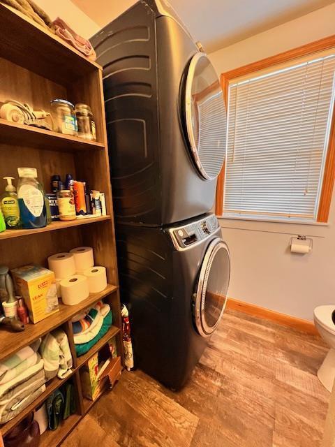 clothes washing area with stacked washer / drying machine and wood-type flooring