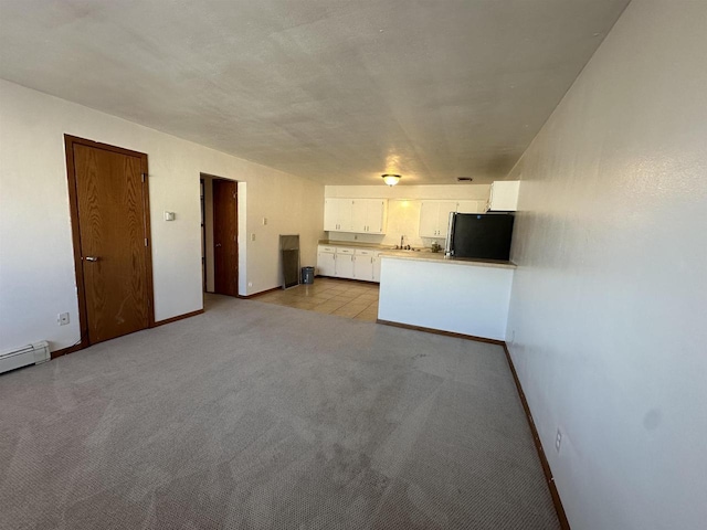 unfurnished living room with sink, light colored carpet, and a baseboard heating unit