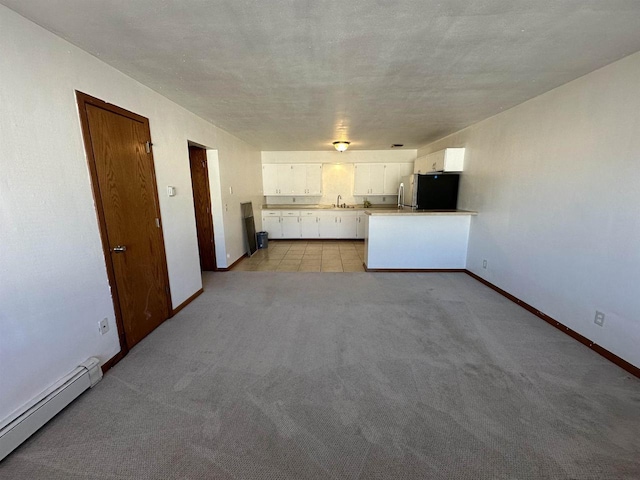 kitchen featuring stainless steel refrigerator, white cabinetry, a baseboard heating unit, light colored carpet, and a textured ceiling