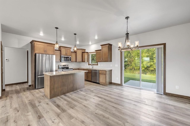 kitchen featuring pendant lighting, appliances with stainless steel finishes, a kitchen island, a chandelier, and light wood-type flooring