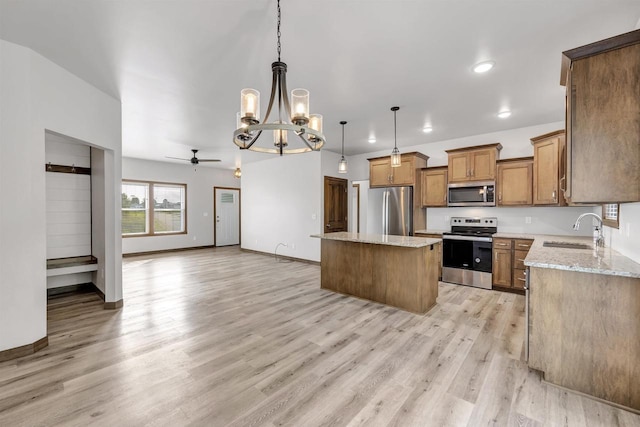 kitchen with sink, hanging light fixtures, stainless steel appliances, a center island, and light stone counters