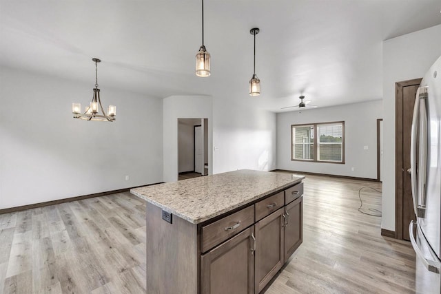 kitchen with a center island, pendant lighting, stainless steel fridge, and light wood-type flooring