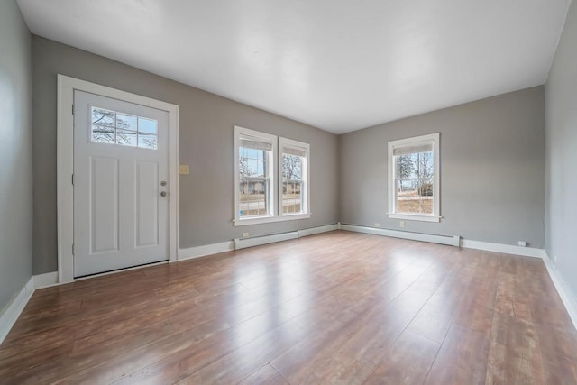 foyer entrance with a baseboard radiator and light hardwood / wood-style floors