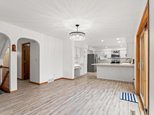 unfurnished living room with sink, a notable chandelier, and light wood-type flooring