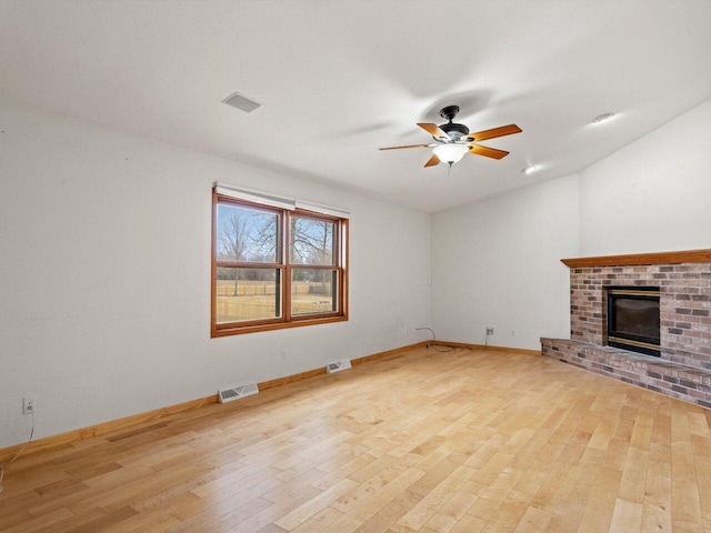 unfurnished living room featuring ceiling fan, a brick fireplace, and light hardwood / wood-style flooring