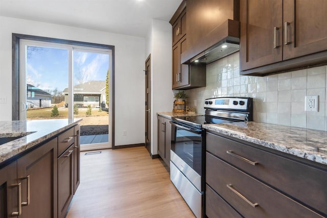 kitchen with stainless steel electric stove, decorative backsplash, custom exhaust hood, light hardwood / wood-style floors, and light stone counters