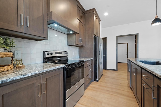 kitchen featuring custom exhaust hood, decorative light fixtures, light wood-type flooring, appliances with stainless steel finishes, and light stone countertops