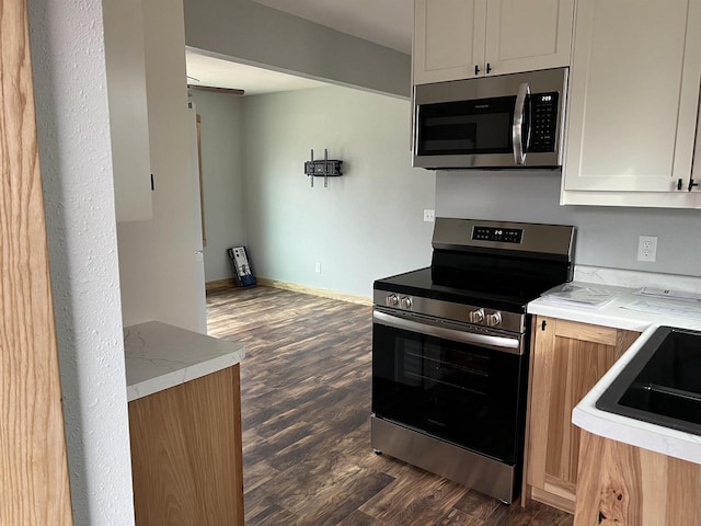 kitchen with dark wood-type flooring, appliances with stainless steel finishes, and white cabinets