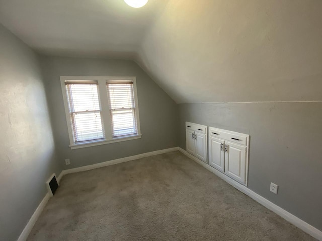 additional living space with light colored carpet and vaulted ceiling