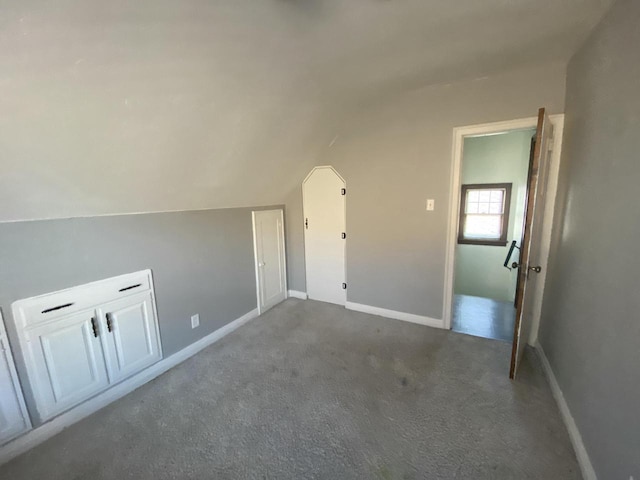 bonus room featuring dark carpet and vaulted ceiling