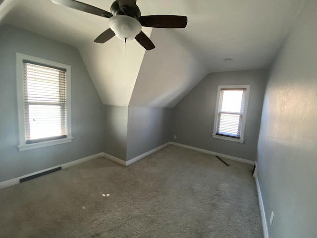 additional living space featuring light colored carpet and vaulted ceiling