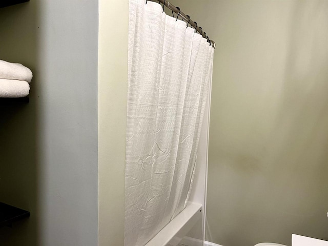 bathroom featuring shower / bathtub combination with curtain and toilet