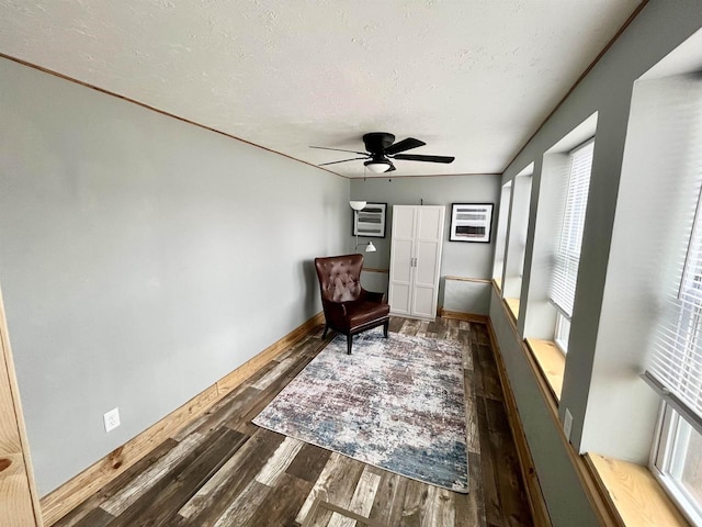 living area with ceiling fan, dark wood-type flooring, and a textured ceiling